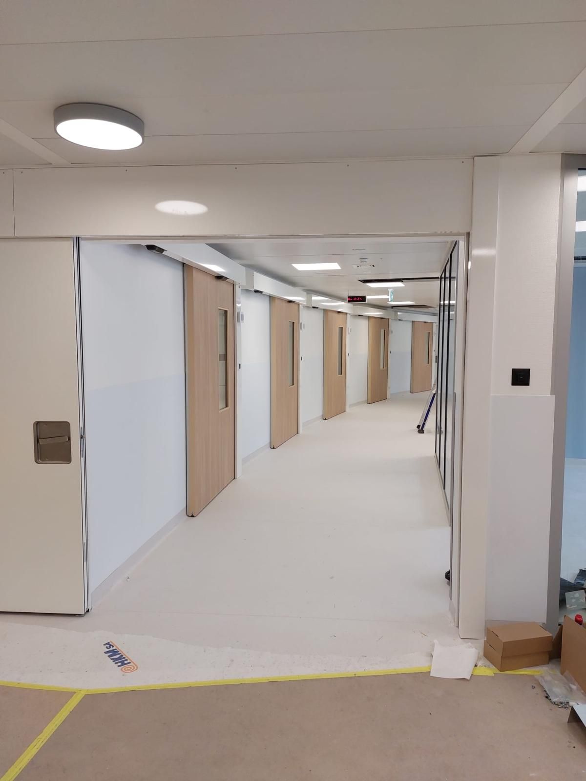 Couloir aux portes coulissantes automatiques en bois, en fin de chantier